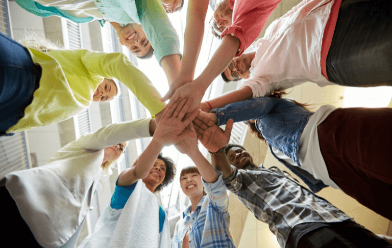 Students put their hands in a pile